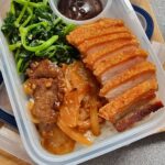 Lunchbox with fried pork, spinach, and rice